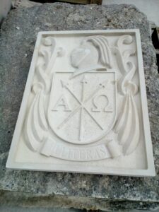 escudo de apellido en piedra con yelmo y lambrequines
